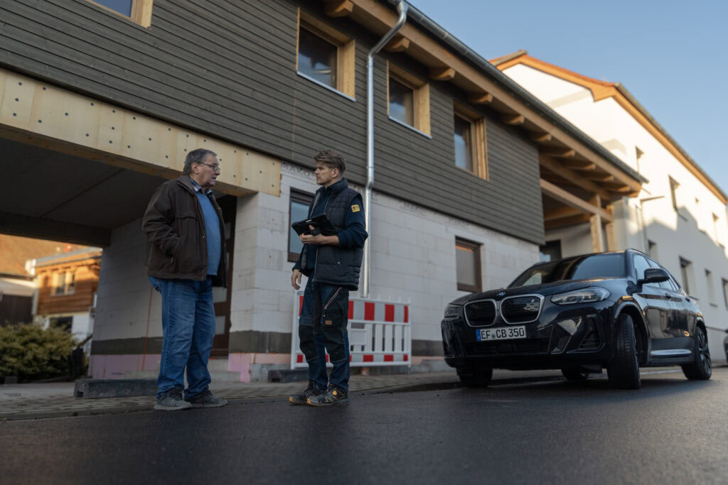 Björn Curth steht zusammen mit einem Architekten vor einem unfertigen Wohnhaus bei Erfurt