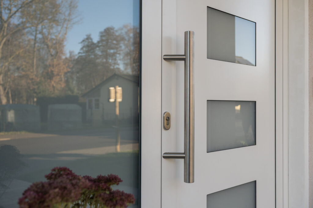 weiße Haustür mit Edelstahlgriff