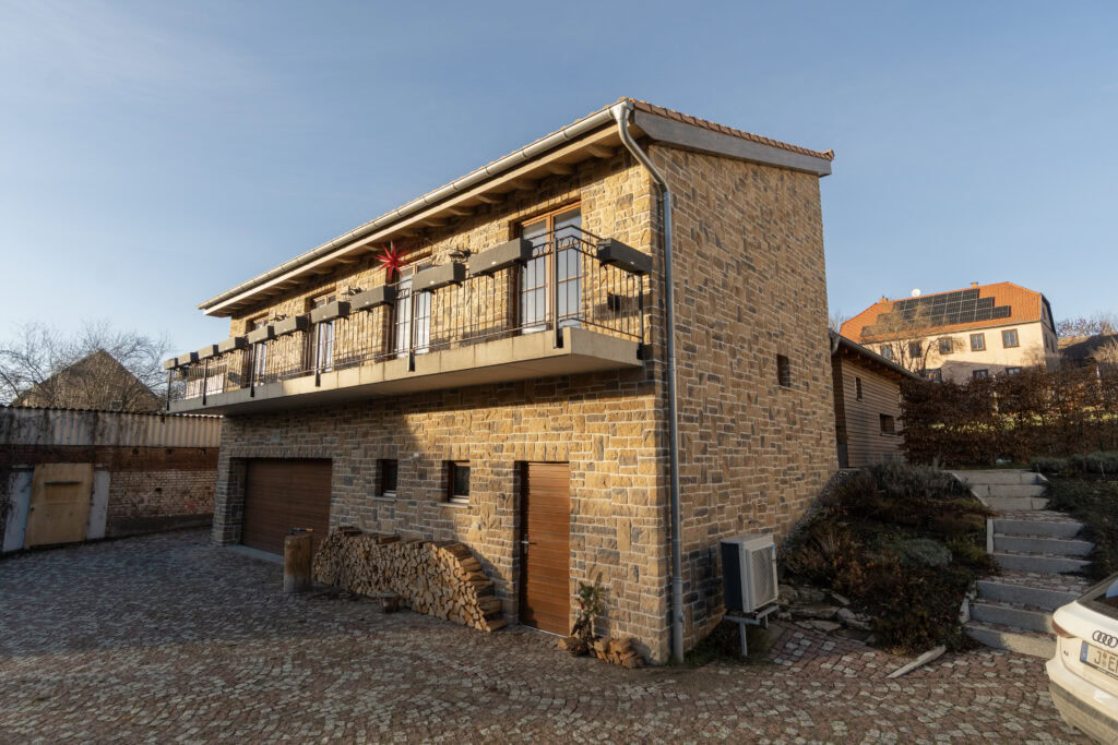 Haus mit Steinfassade bei Erfurt mit langem Balkon und einem Garagentor im EG