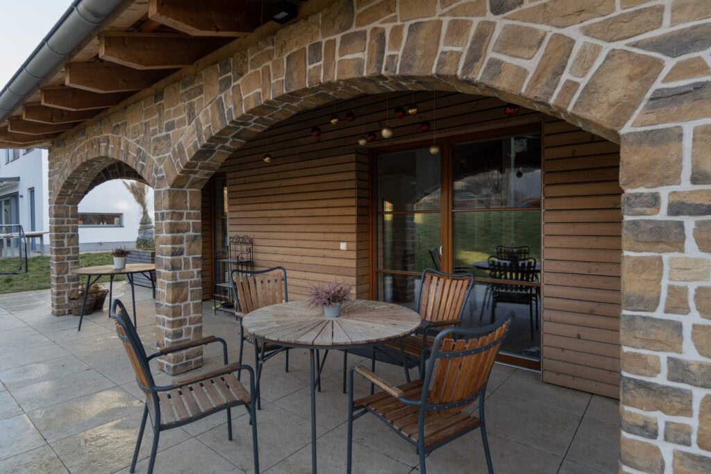 Veranda eines rustikalen Wohnhauses mit Holzfassade und Echtholzfenstern