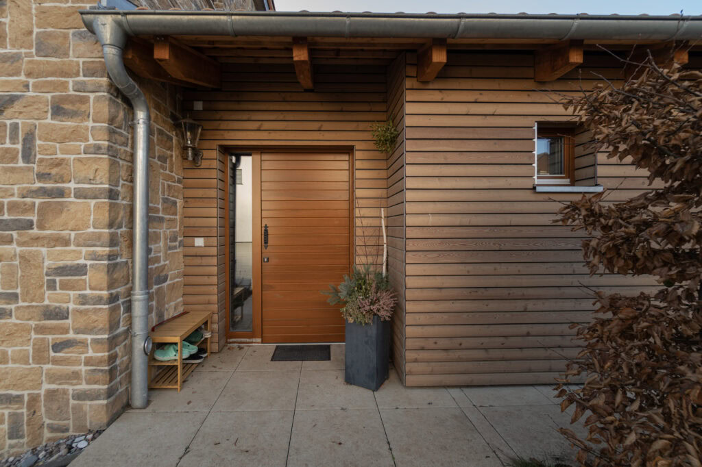 Braune Haustür aus Holz im Eingangsbereich eines rustikal gestalteten Hauses