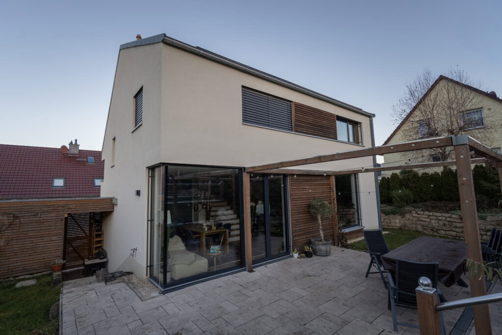 Modernes Einfamilienhaus mit großen Fensterflächen und zweifarbigen Fensterrahmen