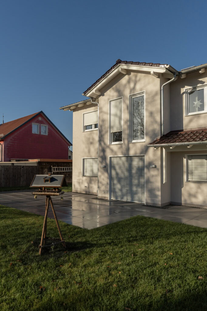 Außenansicht eines Wohnhauses mit Vogelfutterstelle im Vordergrund