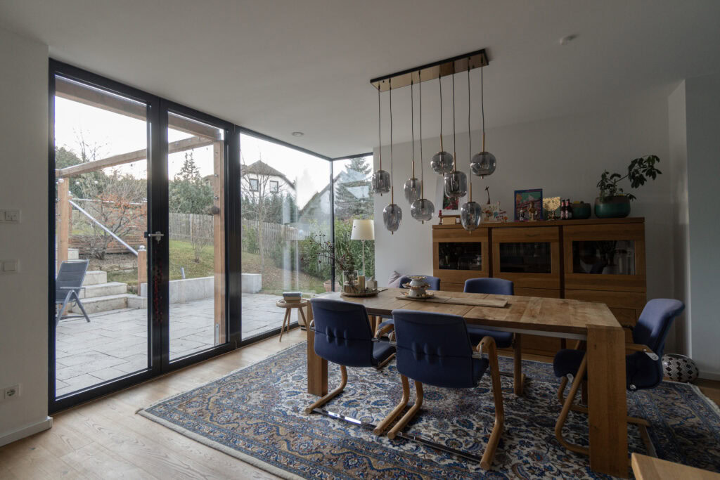 Wohnzimmer mit Esstisch, Stühlen und großer heller Fensterfront